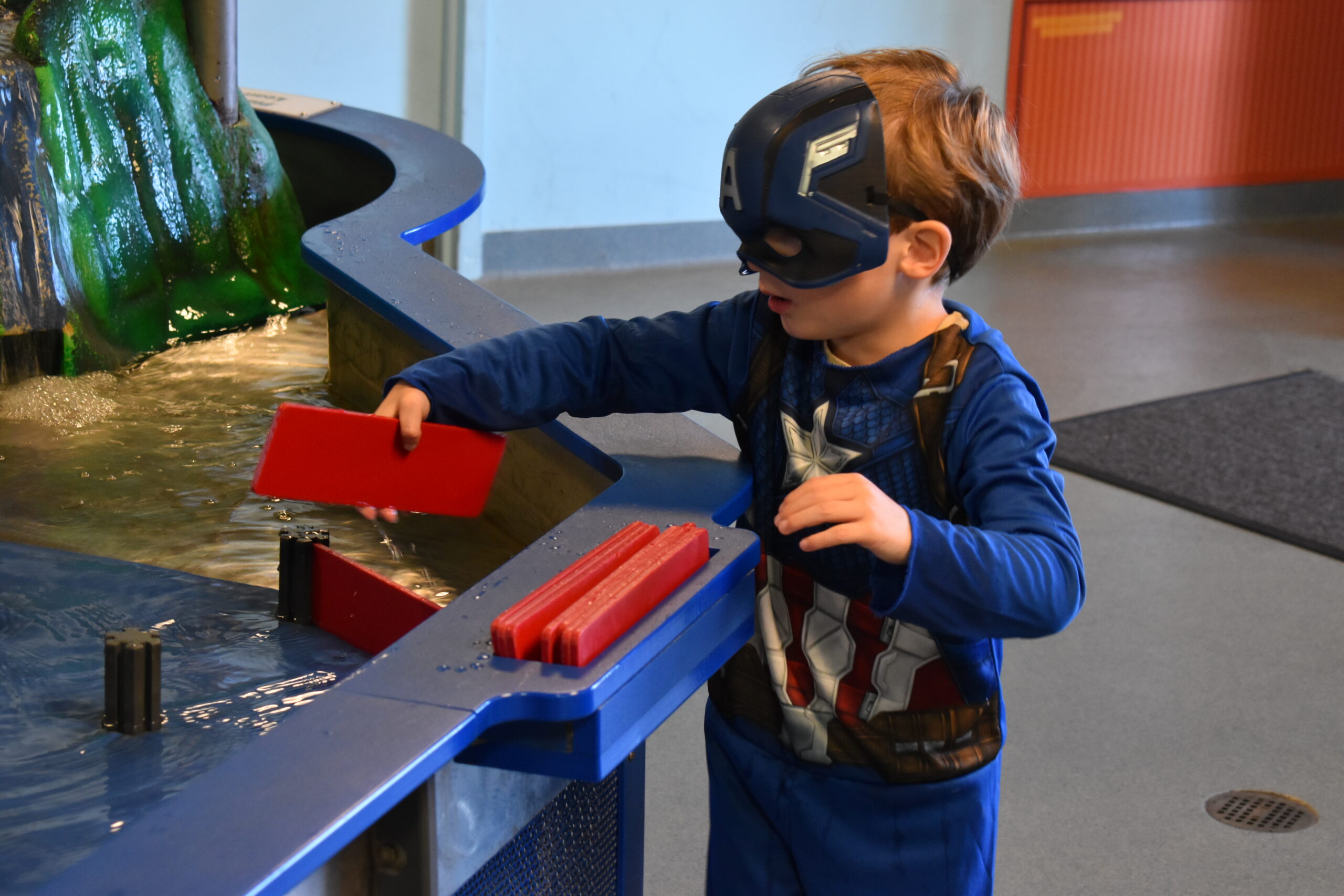 A boy dressed as Captain America playing in our water exhibit