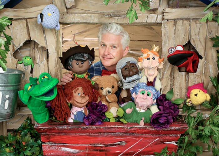 Danny Joe holding puppets in a treehouse.